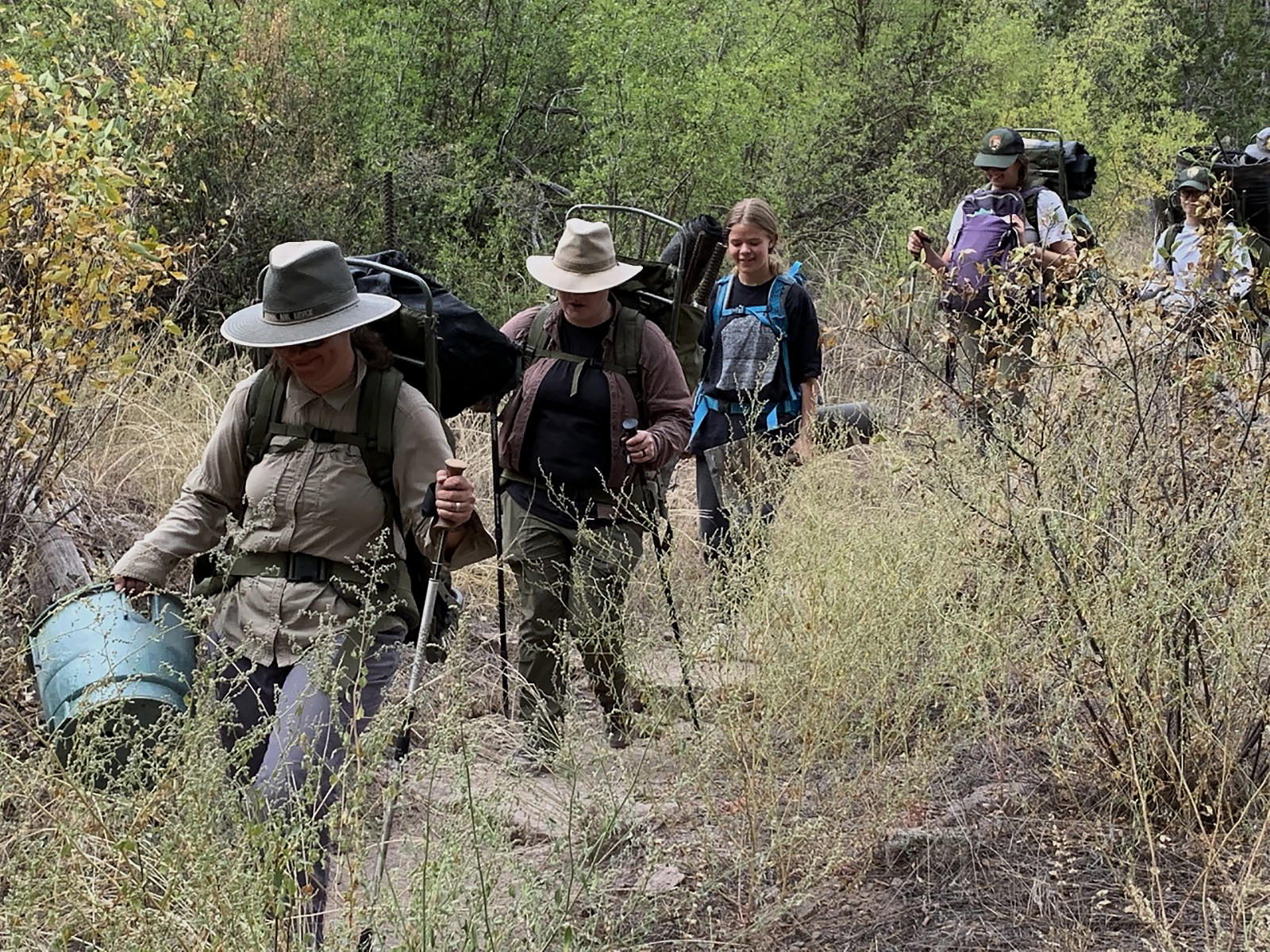 BAND NPLD 3 a group of volunteers hike a trail carrying debris from the wilderness