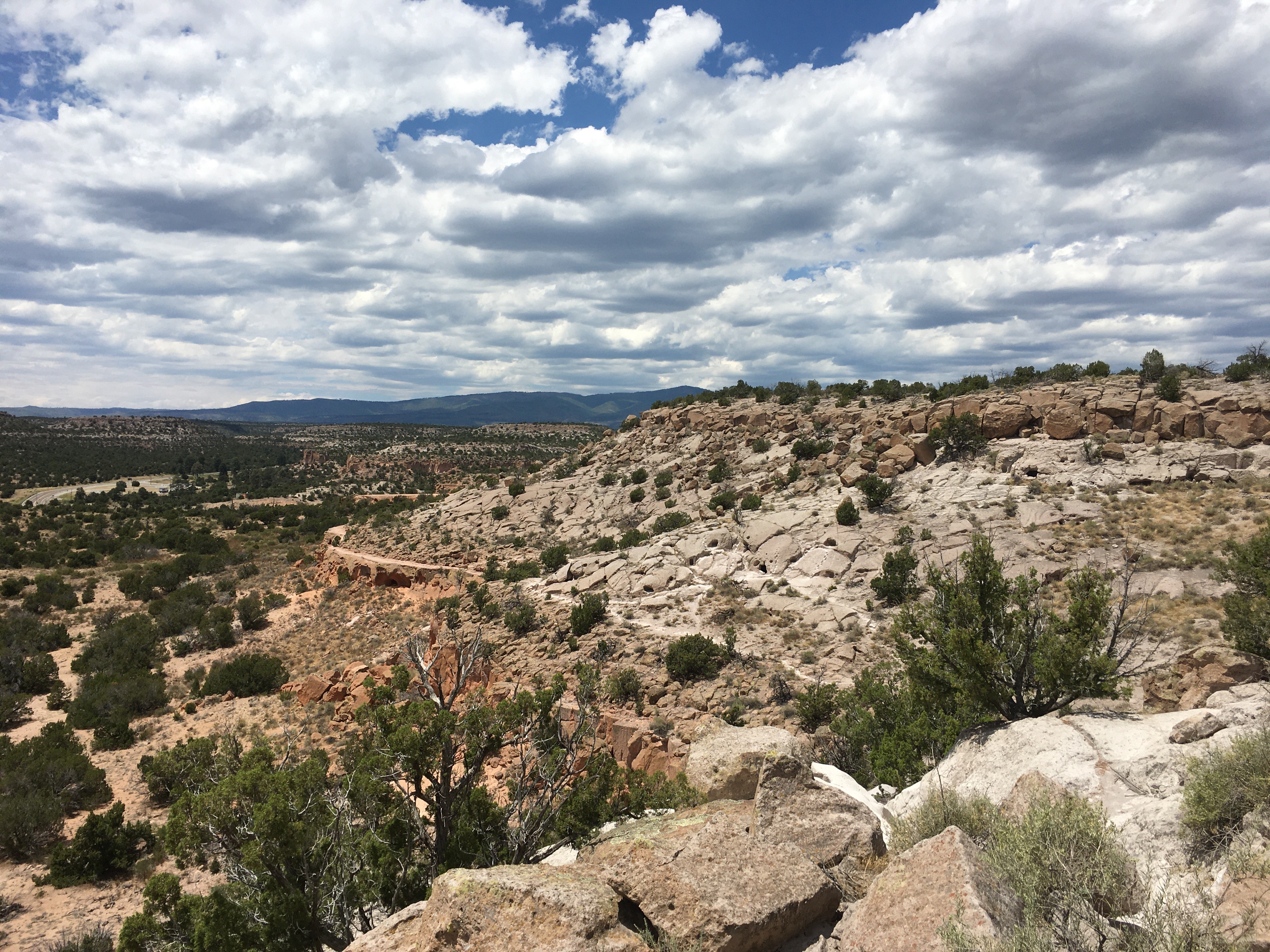 Bandelier National Monument's Tsankawi Unit will remain closed due to power loss at the site. There is currently no projected re-opening date. A view of a rocky landscape with a road in the distance.