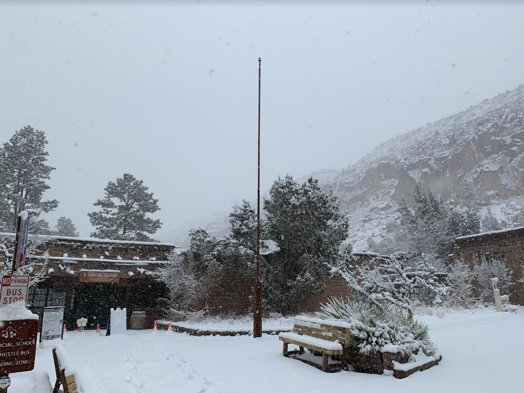 Heavy snow falls onto a building and parking lot.