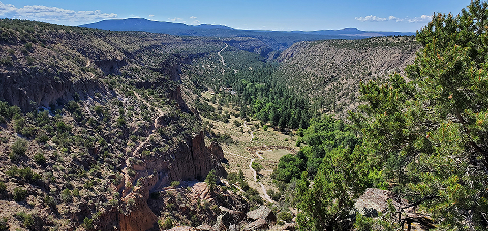 elevated view of a green steep walled canyon with an archeological site