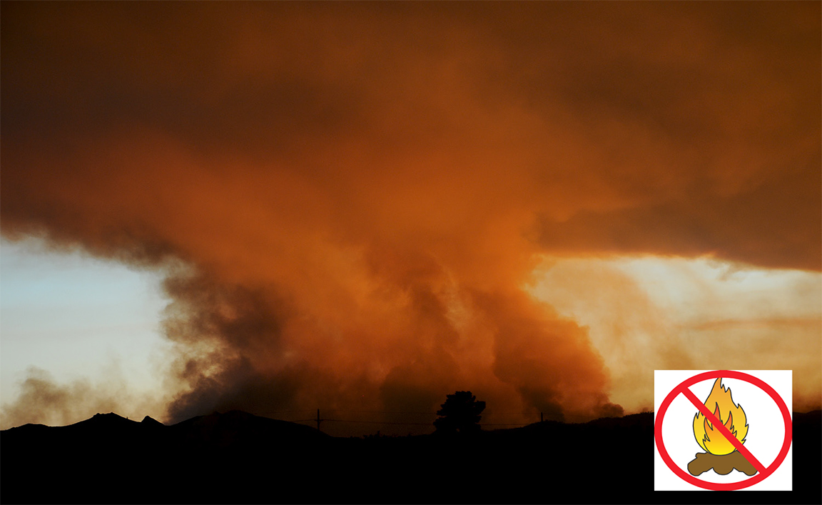 no campfires A large plume of smoke colored orange by the setting sun.