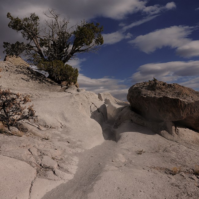 white rock with a carved trail and blue sky with white clouds