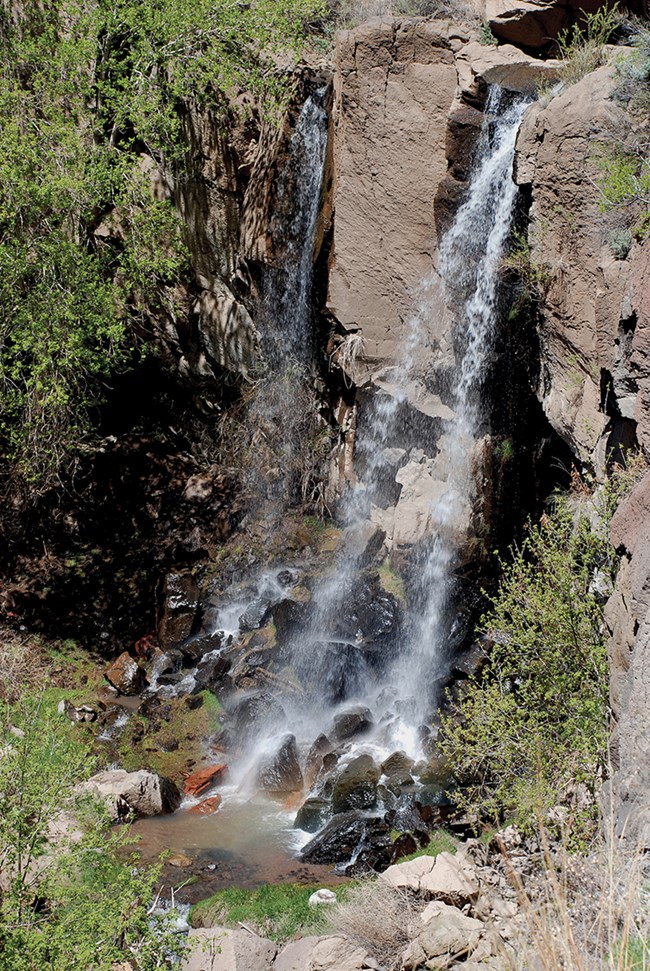 a small waterfall drops over dark rock