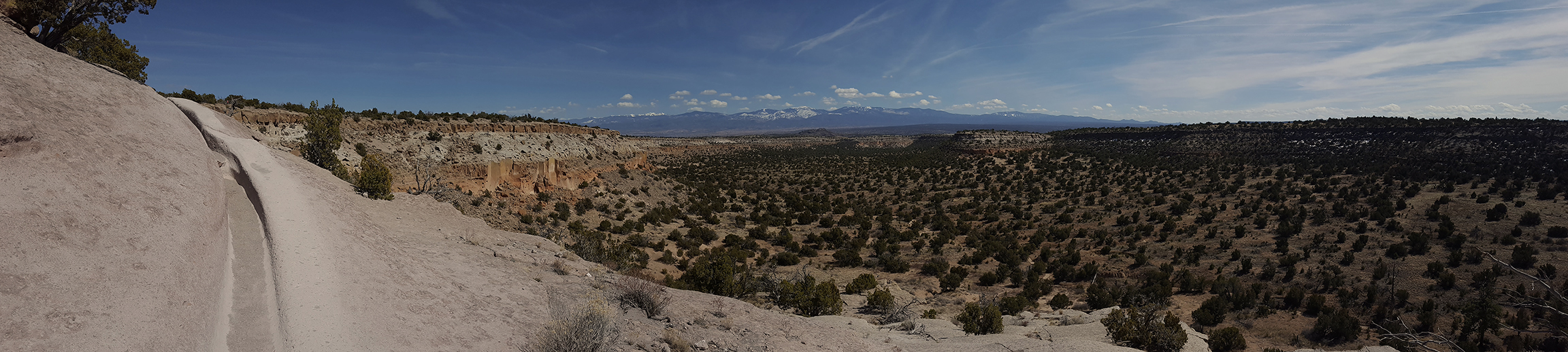 panoramic view with white rock, distant mountains, and a carved trail