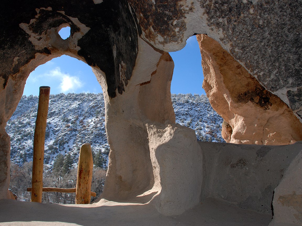 rough stone openings look out at a landscape covered with snow and blue sky