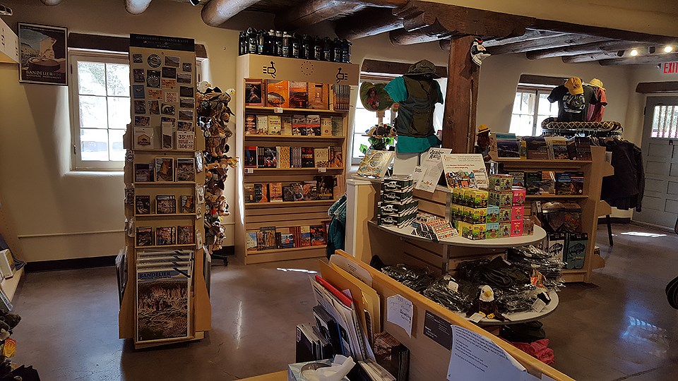 Inside a building with many colorful items for sale, such as books, magnets, posters, clothes, and stuffed animals.