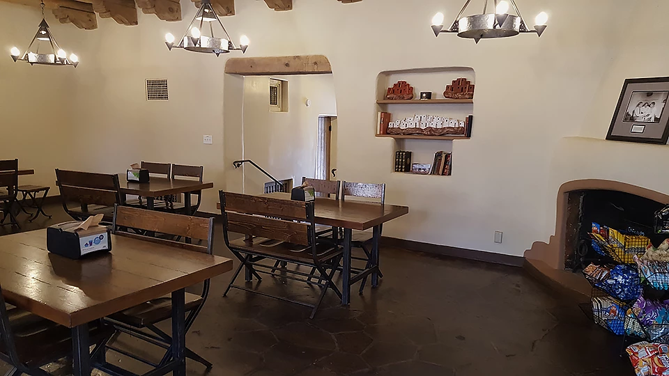 Inside the restaurant. Inside a building. Tables and chairs are to the left, and a fireplace is to the right.