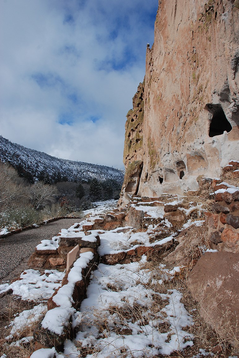 the remnants of stone structures along the base of a steep canyon wall
