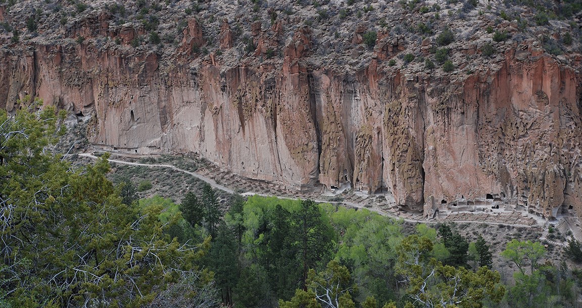 a wide view of the remnants of dwelling along the base of a cliff