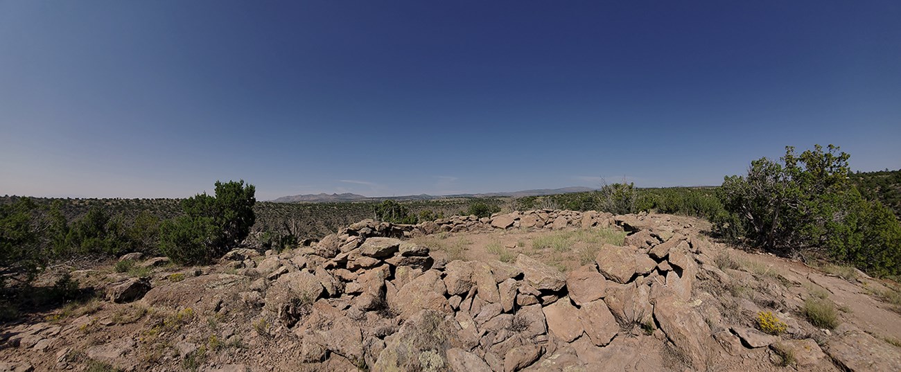 remnants of a stone structure in the foreground and a steep walled canyon in the background