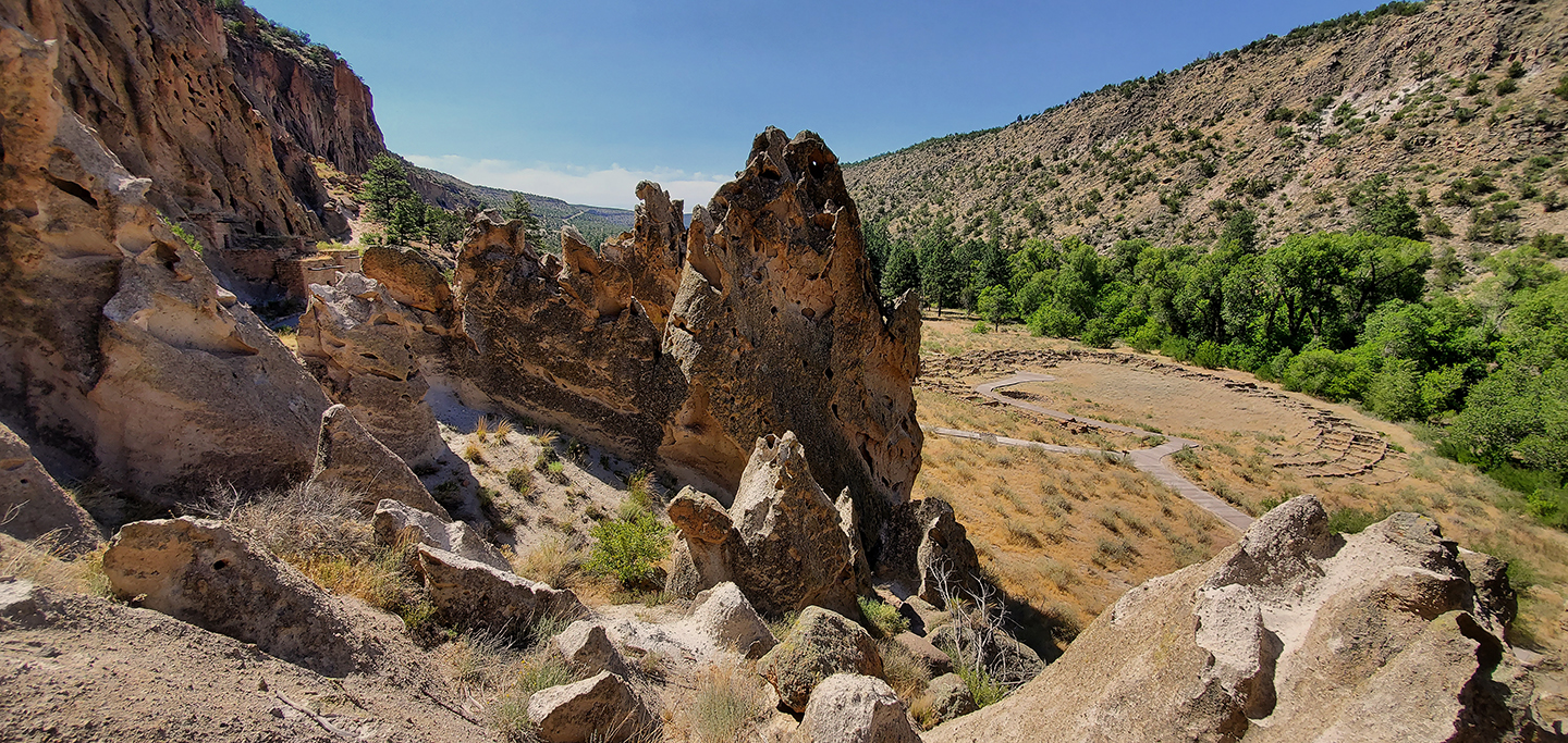a view of a canyon with the remnants of a large stone structure, green trees in the background.