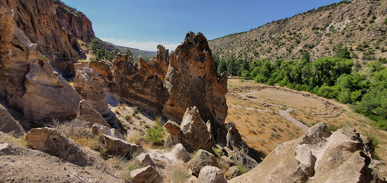 a view of a canyon with the remnants of a large stone structure, green trees in the background.