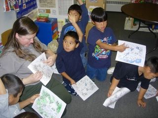 A ranger and five children sit on the ground with a worksheet from the Water Education Kit A ranger and five children sit on the ground with a worksheet from the Water Education Kit