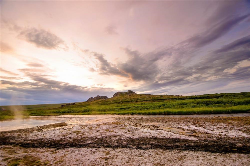 Wispy clouds move through pastel skies above Serpentine Hot Springs.