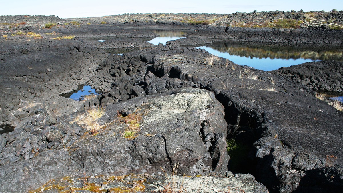 Dark lava flow with rain ponds in depressions Dark lava flow with rain ponds in depressions