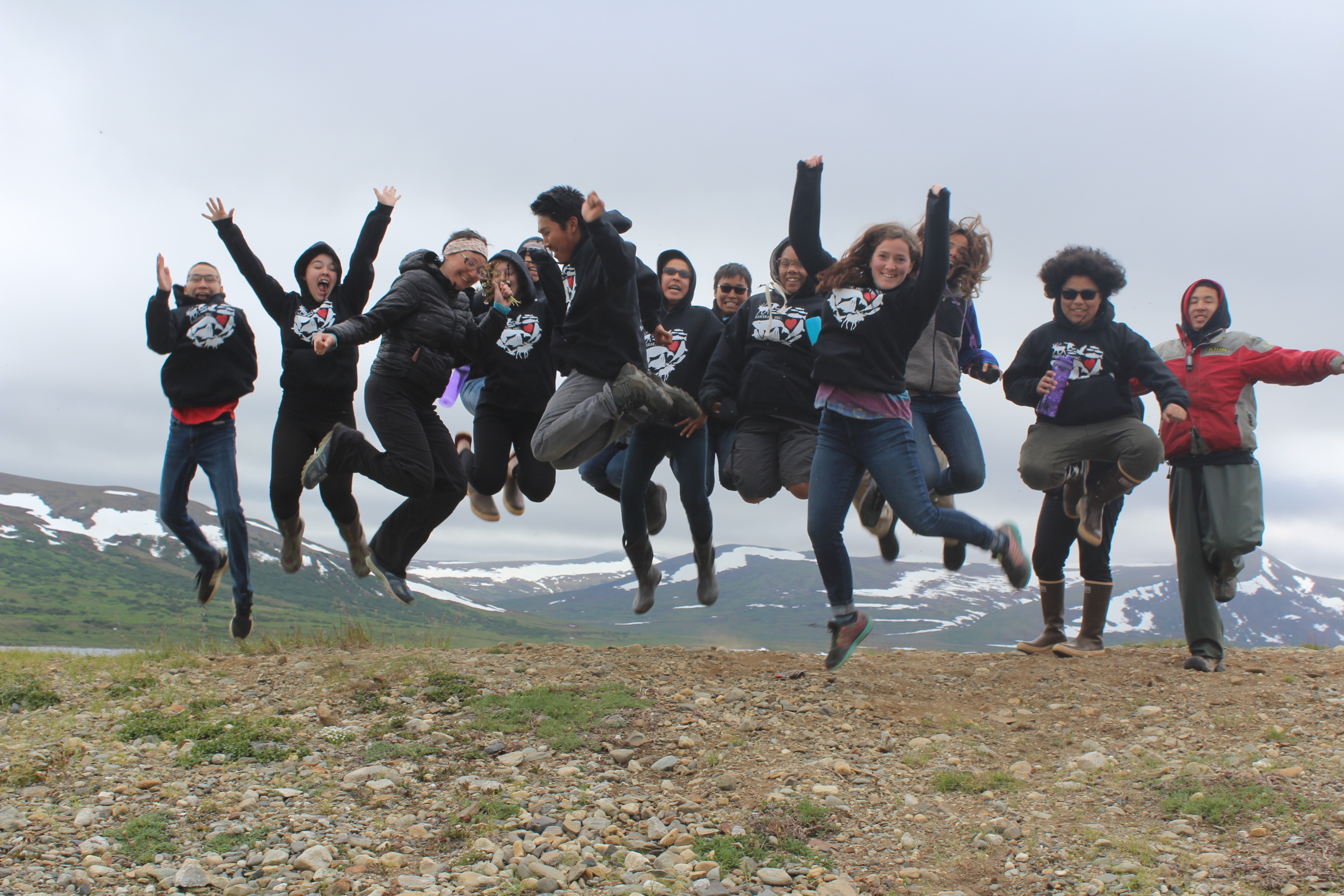 A group of kids and adults are caught jumping mid-air.