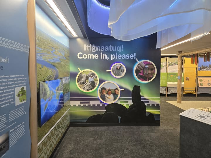Image to be used for Press release A photo depicting the entrance into the new Bering Land Bridge Heritage Center. In the photo, there are images of children with big smiles, Words that say "Please come in" and a replication of the northern lights hanging from ceiling.