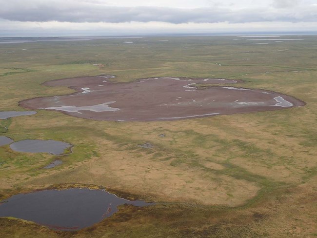 Aerial view of a drained lake. From above, a drained lake is surrounded by a grassy landscape.