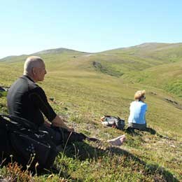 Two people relaxing on green undulating hills.