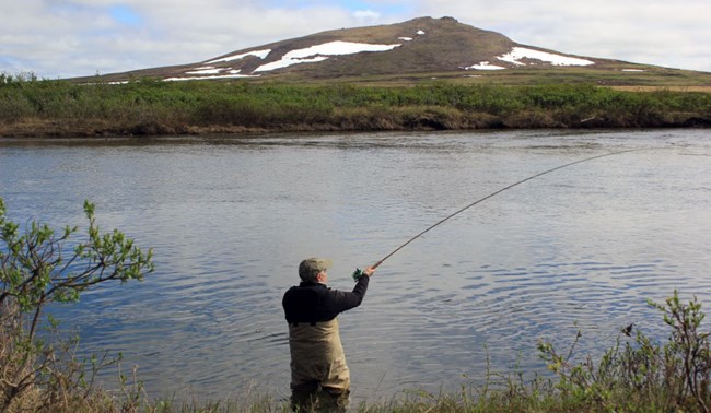 Man fishing along river