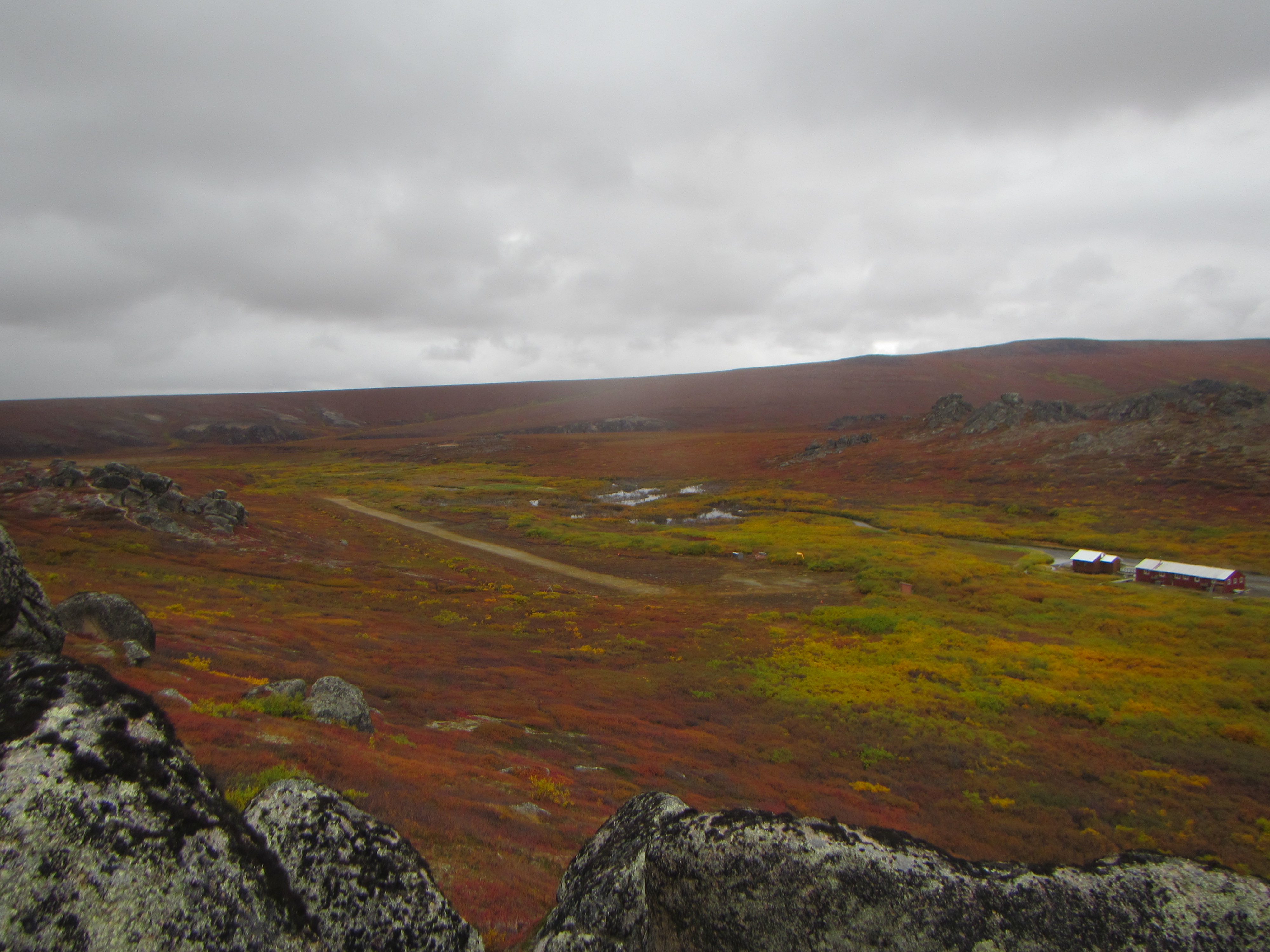 The Serpentine airstrip extending across the red and green tundra. On the right, the Serpentine bunkhouse and bathhouse sit next to Hot Springs Creek.