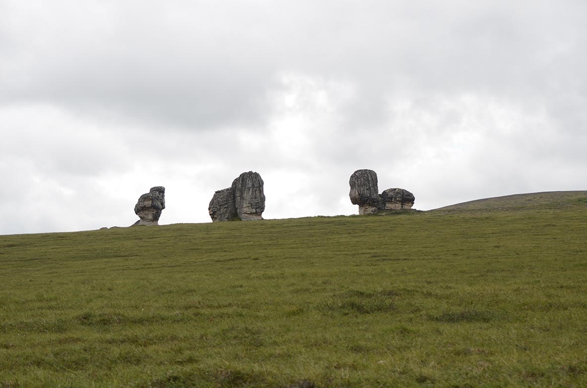 In a vast grassland, three granite monoliths stand in isolation.