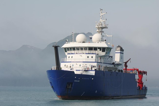 Research boat on the water with mountains in the background.