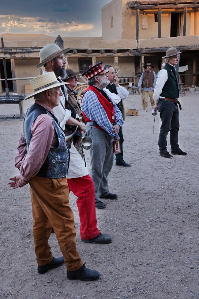 Men in period costume stand in the plaza of Bent's Fort