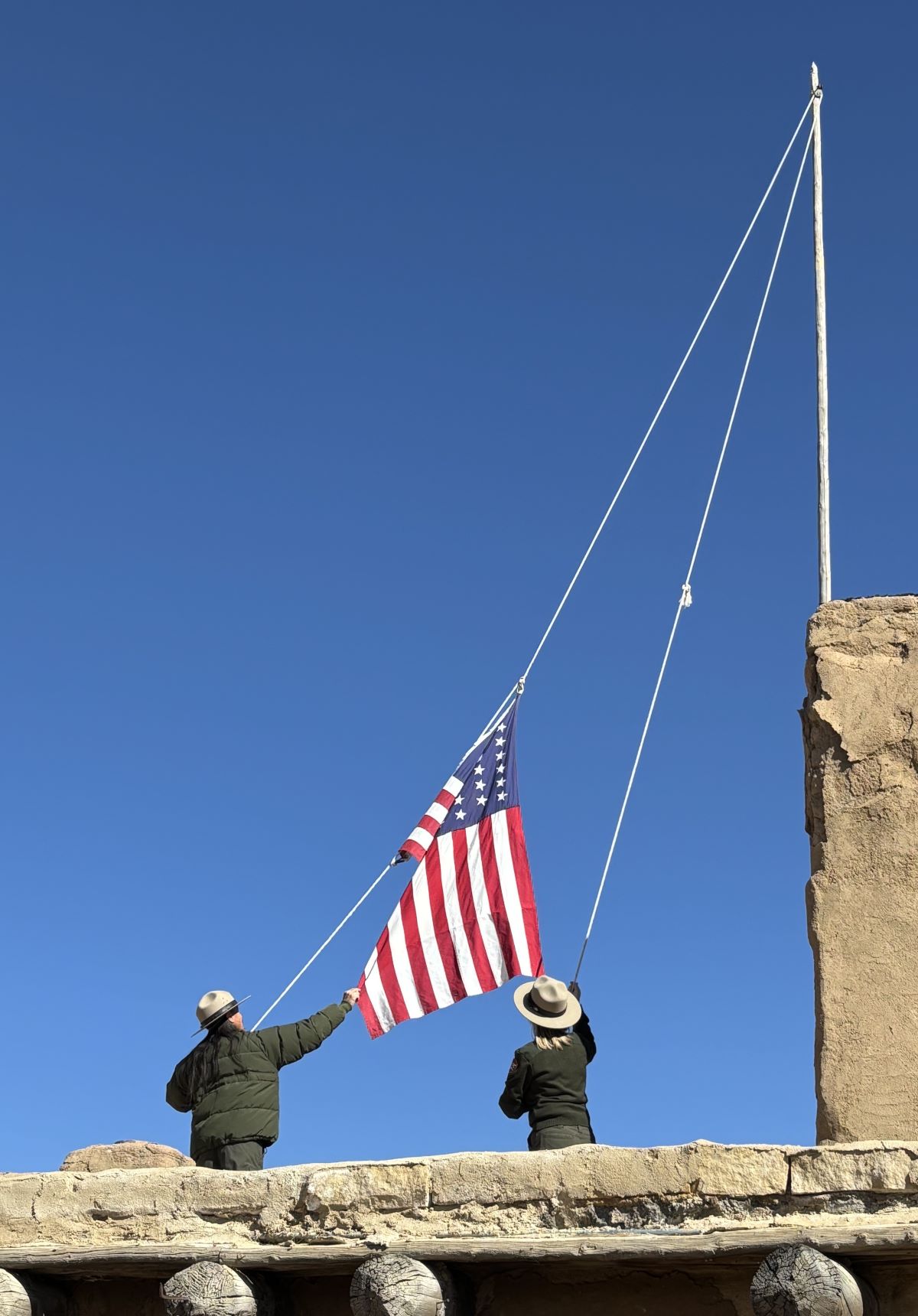 Two rangers raise flag at watchtower