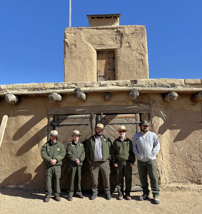 Five uniformed staff members stand in front of fort zaguan door