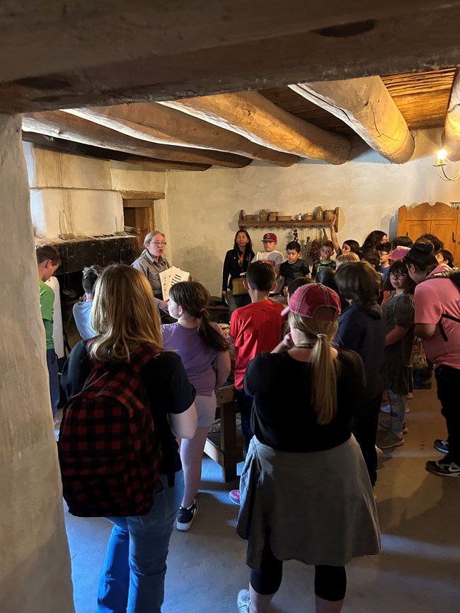 Park ranger speaks to students in a small room before a fireplace