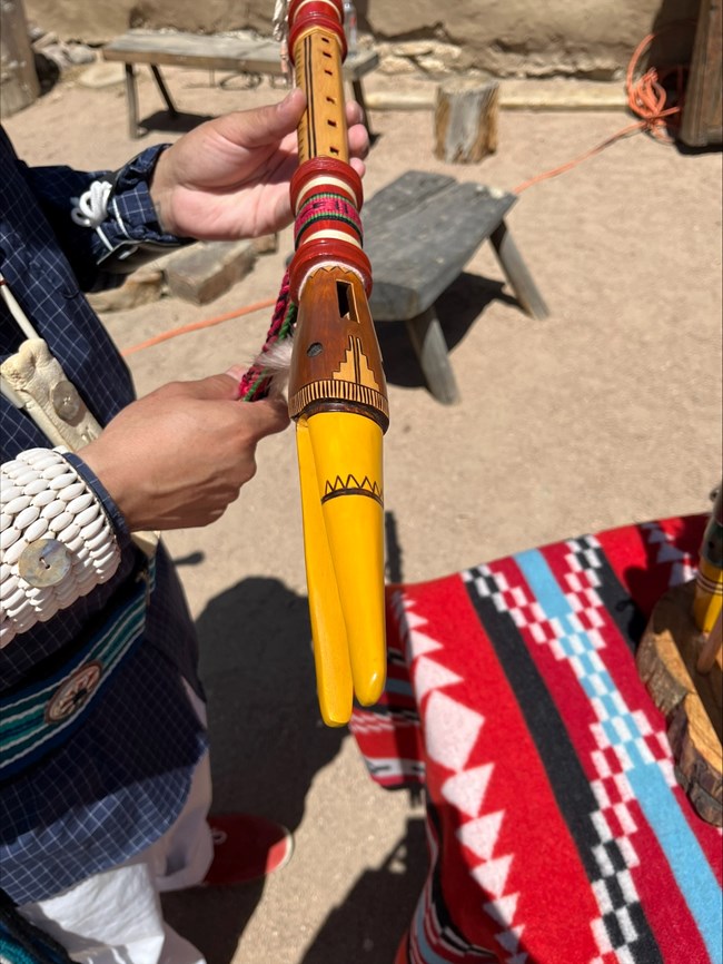A man holds a wooden flute