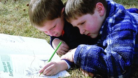 Two children working on activities in a Junior Ranger book