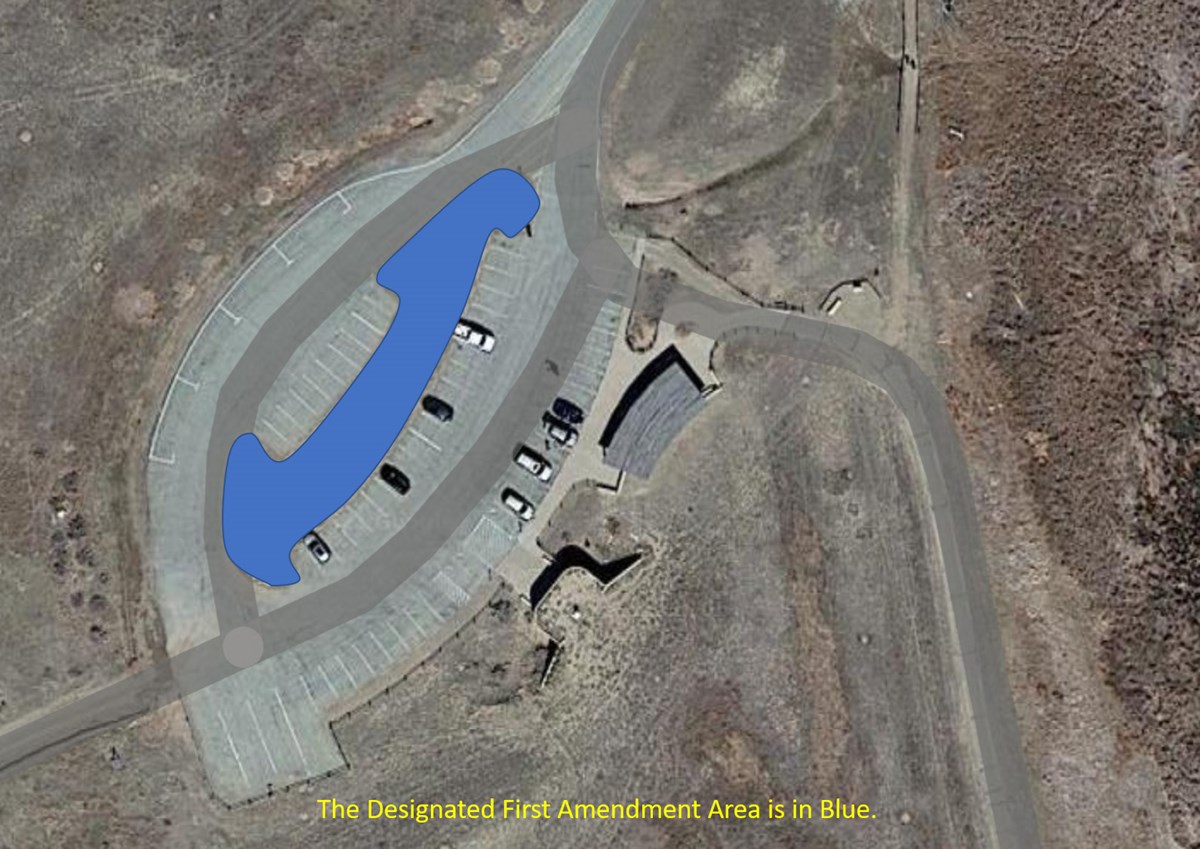 Photo of the parking lot at the Comfort Station at Bent's Old Fort National Historic Site with the Designated First Amendment Area indicated in Blue (grassy area within the visitor parking lot).