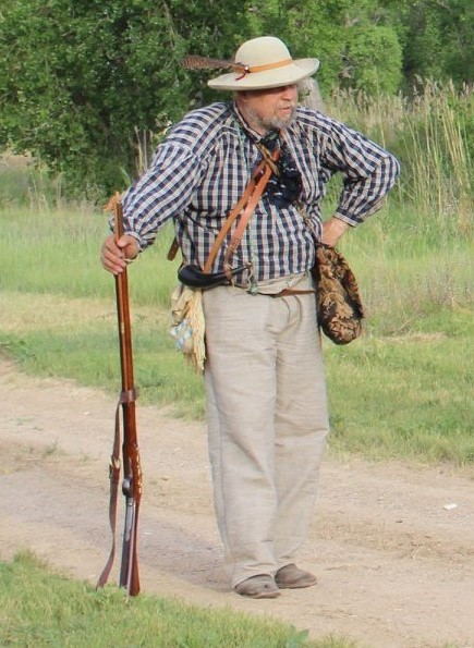 A man dressed in the clothing of a historic mountain man.