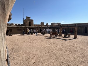 Park rangers speak to a group of visitors inside the plaza of a large building.