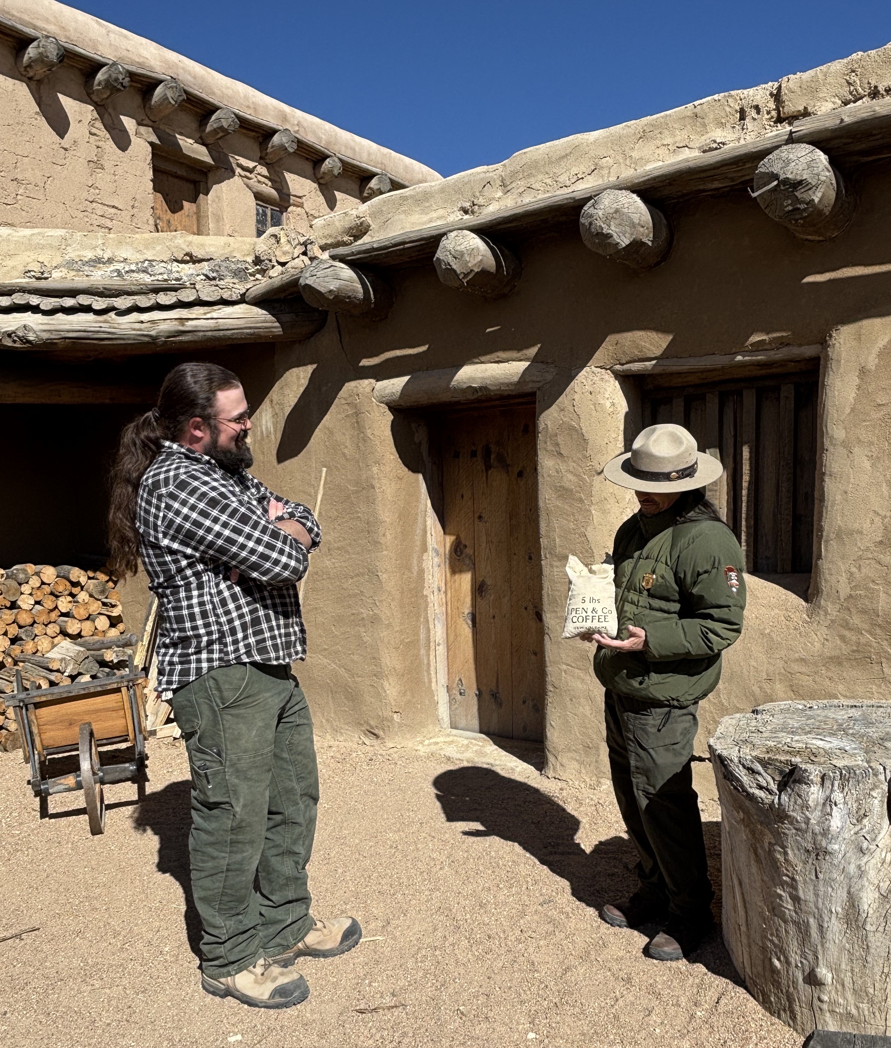 A park ranger holds a replica trade item while conversing with a visitor A park ranger holds a replica trade item while conversing with a visitor