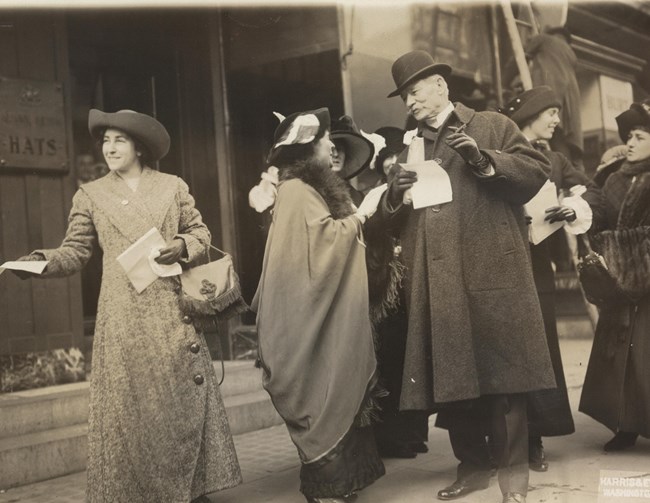 Photograph of suffragists handing out materials to people passing on street