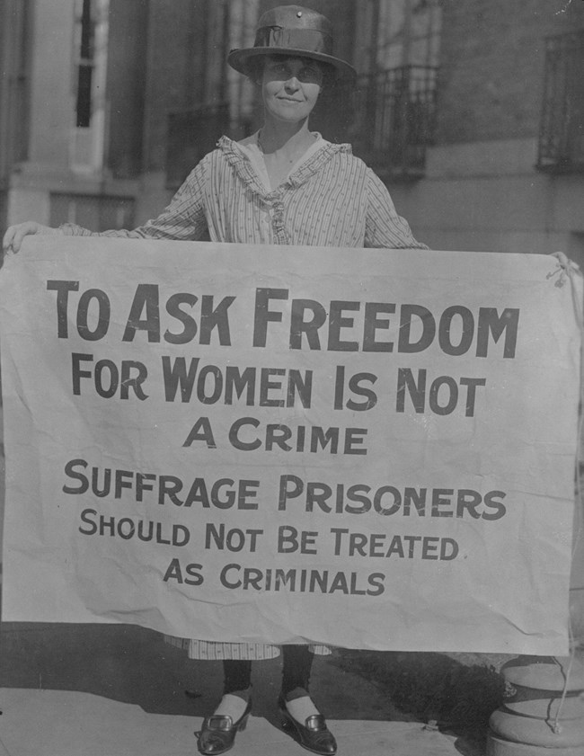 Mary Winsor holding a large banner in both hands