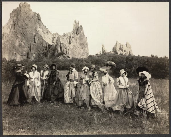 Women Pioneers Garden of Gods Photograph of group of women in nineteenth-century costume standing outside, large rock formation in background.
