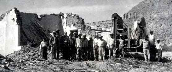 Men standing in front of the ruins of Chata's restaurant, 1957.
