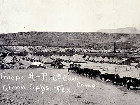 A 1916 photo shows rows of tents and horse in a remote desert army camp.
