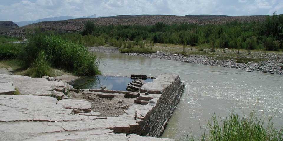 Remains Of Bath House The stone foundation of a hot springs bath house remains abuts a river.