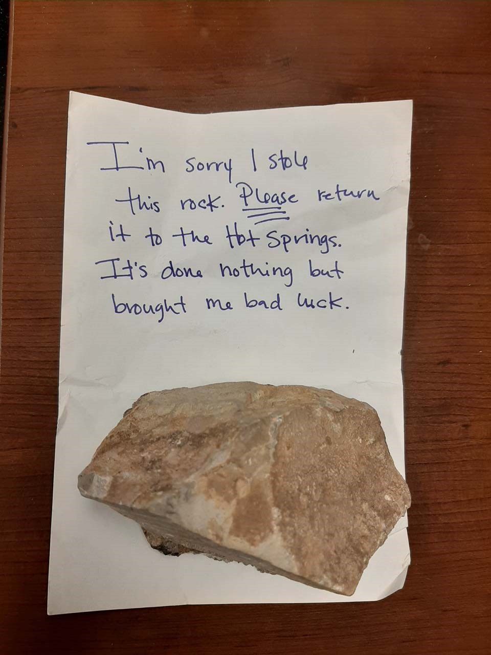 A handwritten note with a rock has an apology for stealing it.