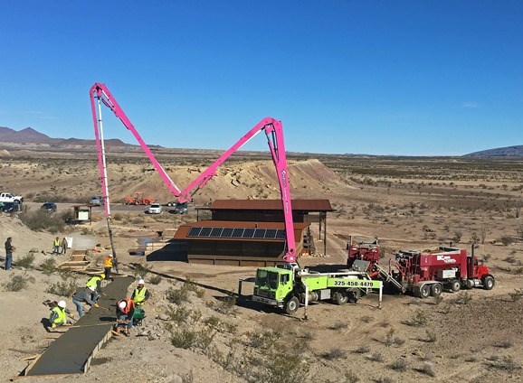 Workers pouring concrete on a trail.