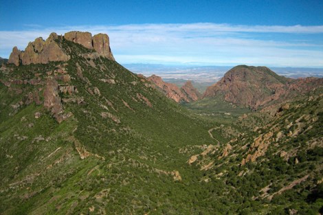 A view looking down on mountain tops that surround a lower basin.