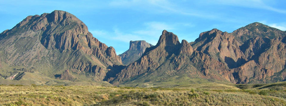 Rugged brown mountains rise above a desert landscape.