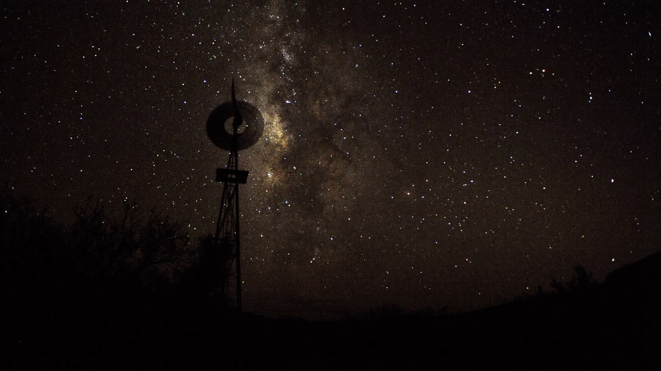 A windmill is framed against a starry sky