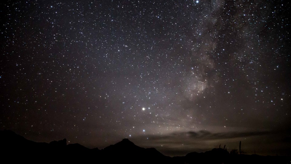 A sky filled with stars towers over the desert landscape