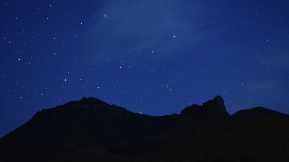 Dark mountains beneath a night sky